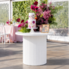 White ripple round display table with a ribbed pedestal base, styled for cakes, floral arrangements, signage, and elegant event décor.