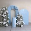 Light blue bliss baby package for baptism backdrop setup with floral columns and white baby’s breath arrangements.
