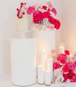 Set of 2 white plinths with red and white floral arrangement and candles – elegant event decor rental by Magic Flowers Event Rentals Toronto