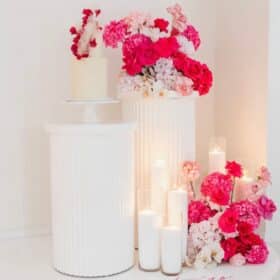 Set of 2 white plinths with red and white floral arrangement and candles – elegant event decor rental by Magic Flowers Event Rentals Toronto