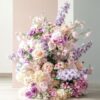 Pastel pink, lavender, and cream silk floral arrangement with roses, hydrangeas, and delphiniums