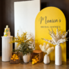 Lemon Blossom Package featuring a yellow arch backdrop with custom bridal shower lettering, white panel, lemon baskets, white vases, yellow florals, greenery, and a cake plinth.