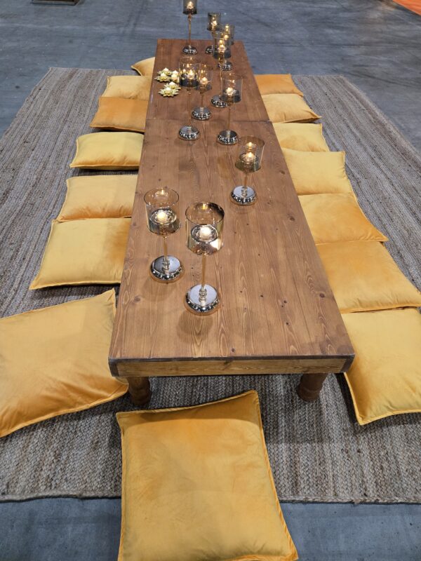 Golden boho low table lounge with mustard floor cushions, wooden table, and candle decor at a corporate event in Toronto