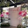 Large white square engagement backdrop with "We are Engaged" script and oversized pink and white handcrafted flowers for an event rental in Richmond Hill.