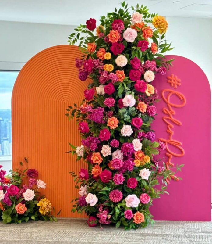 Corporate event decor setup in Downtown Toronto featuring a custom backdrop rental and vibrant floral arrangements for a Pride celebration.