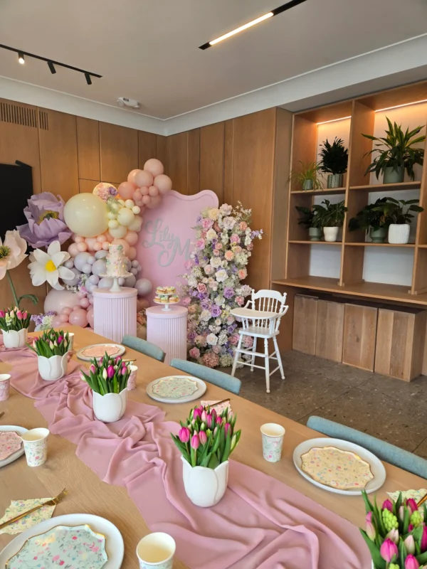 Pastel themed kids birthday party decor featuring a wavy pink backdrop, balloon garland, giant flowers, plinths, and a floral table setup at Summerhill Event Boutique in Toronto.