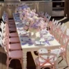 Fairy butterfly kids table setup with pink chairs, white butterfly wings, pastel floral centrepieces, and lavender place settings.