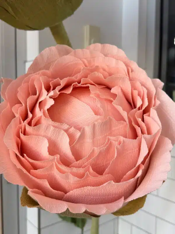 Close-up of a handmade giant peach paper flower with intricate ruffled petals, crafted for the Lush Cosmetics corporate event setup.