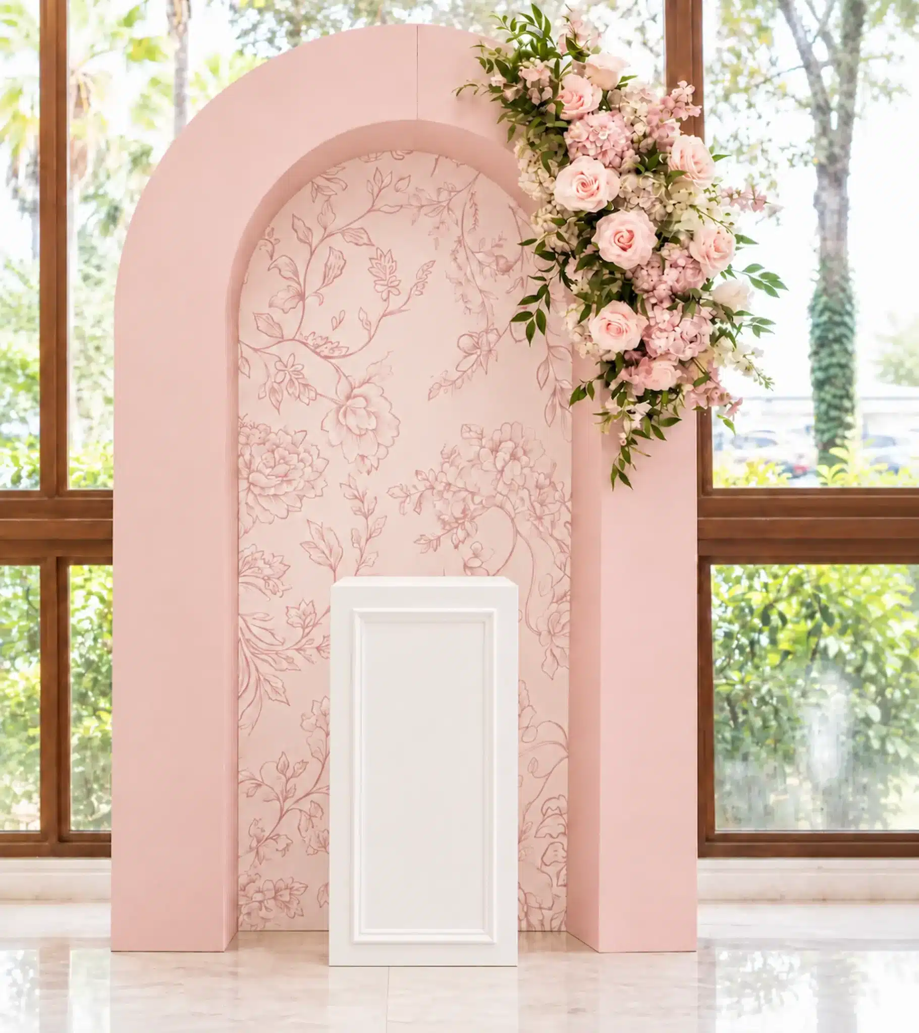 Blush pink floral package with a soft floral-patterned centre panel, cascading pink and ivory flower arrangement, and white framed plinth for elegant events.