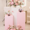 Elegant floral plinth display featuring three white and baby pink plinths decorated with luxurious blush pink, baby pink, and white floral arrangements, including peonies, roses, and hydrangeas. Perfect for beauty salon grand openings, corporate events, product launches, and luxury celebrations in Toronto and the GTA.