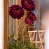 Burgundy Giant Bloom Garden on tall sculptural stems with green leaves and a lush botanical base of ferns, eucalyptus-style greenery, and foliage.