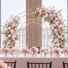 Double floral arch backdrop featuring cascading floral arrangements of baby pink roses, white hydrangeas, blush peonies, and lush greenery. Romantic floral arch displayed behind a beautifully decorated sweetheart table with pink and white centrepieces and candles. Luxury wedding arch rental in Toronto and the GTA by Magic Flowers Event Rentals.